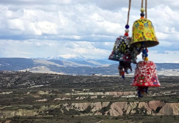 Uçhisar'dan Erciyes Dağı’na uzanan manzara ve ön planda seramik süs çanları